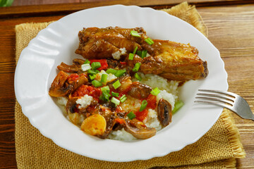Thai chicken with rice and vegetables in a white plate on a linen napkin next to a fork