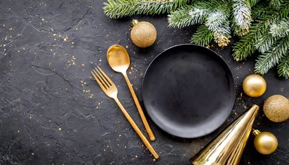 Foto op Plexiglas christmas table setting with empty black ceramic plate fir tree branch and gold accessories on black stone background top view copy space © Deven