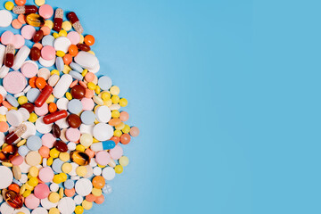 Colorful pills and capsules on blue background. Minimal medical concept. Copy space