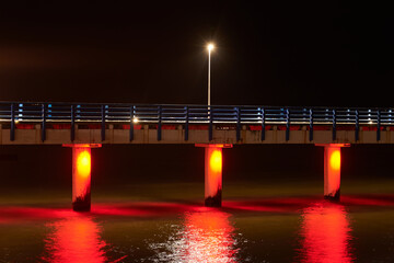Sea pier adorned multicolored twinkling lights at night symbolizes charm and allure of coastal...