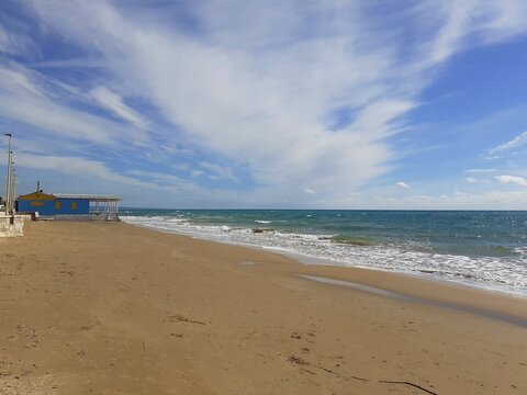 Il mare d'inverno, il cielo blu con qualche nuvoletta bianca, la spiaggia deserta, una biccola baracca sulla spiaggia.