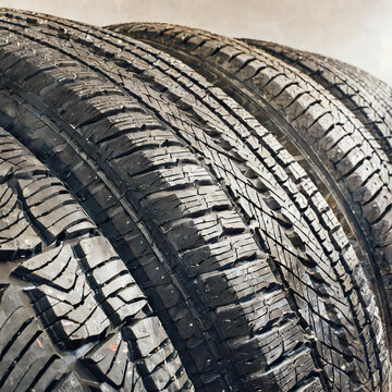 Winter tires with structured adhesion surface in line. New black car rubbers in studio shot. Dark unused wheels for safety drive.