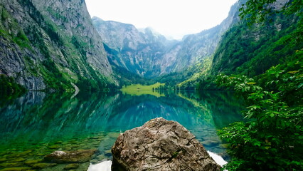 Naklejka na ściany i meble Konigssee, Germany - 06.16.2018: Obersee on a sunny day with peaceful water and forest on the side