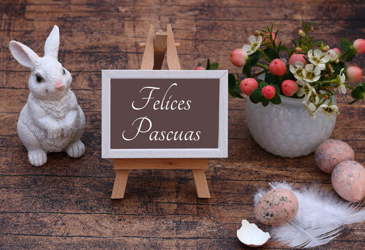 El texto Felices Pascuas escrito en un caballete con adornos y flores de Pascua.
