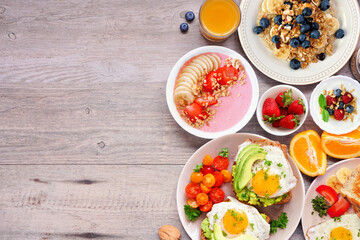 Healthy breakfast or brunch side border on a wood background. Top view. Avocado toast, smoothie bowls, oats, yogurt and a collection of nutritious foods.