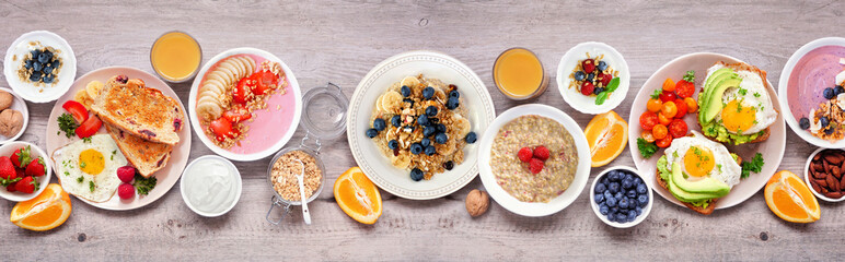 Fototapeta na wymiar Healthy breakfast or brunch table scene on a wood banner background. Top view. Avocado toast, smoothie bowls, oats, yogurt and a collection of nutritious foods.