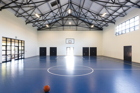 An empty basketball court awaits players at a school gym