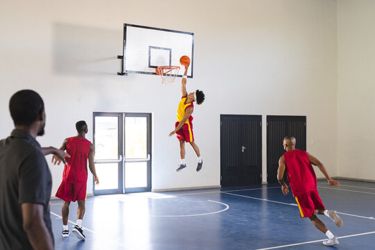Young African American man jumps for a slam dunk in a basketball game at a gym