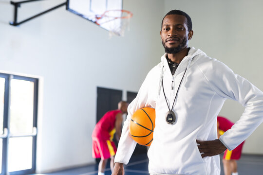 African American coach stands confidently in a gym, with copy space
