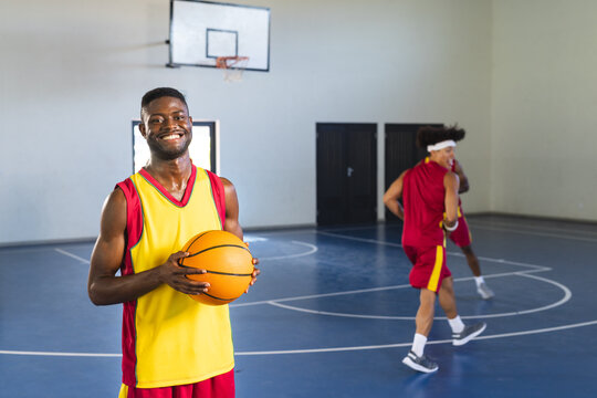 African American man holds a basketball in an indoor court, with copy space