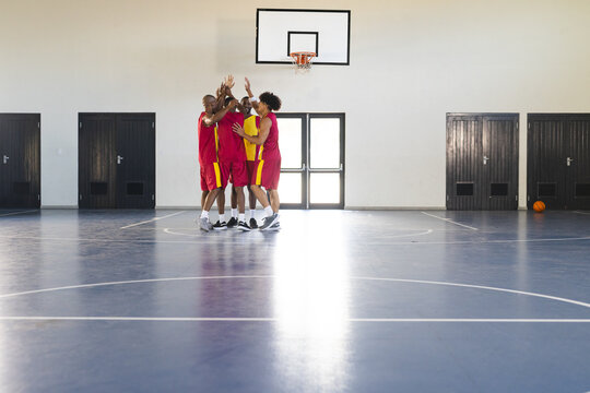 African American men celebrate a basketball victory in a gym, with copy space