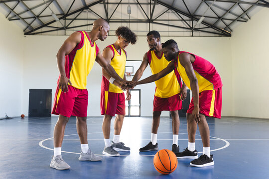 Diverse basketball team huddles in an indoor court