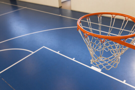A basketball hoop stands ready for action in an indoor gym with copy space