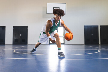 Young biracial man plays basketball indoors