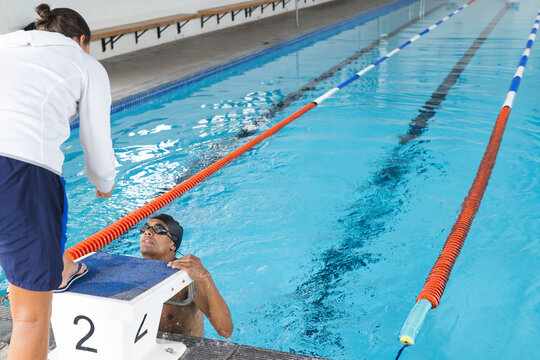 Swimmer receives guidance from his coach at the poolside, with copy space