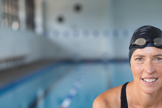 Caucasian female athlete swimmer smiles at the poolside, with copy space