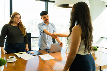 Latin recruiter greeting a candidate with a handshake before begining their interview