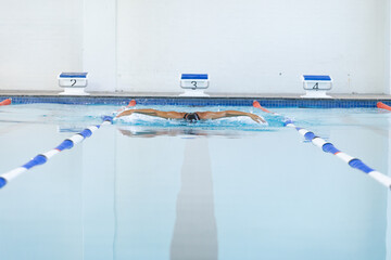 A swimmer practices in a pool lane, with copy space