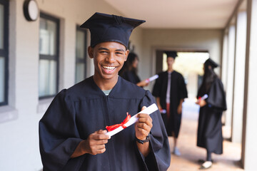 Beaming graduate holds his diploma at high school
