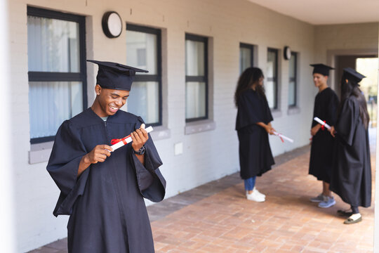 Teenage biracial boy in graduation attire at high school
