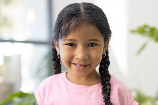 A biracial girl smiles brightly indoors