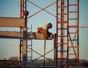 Iron worker wearing a hard hat and sitting on a steel beam