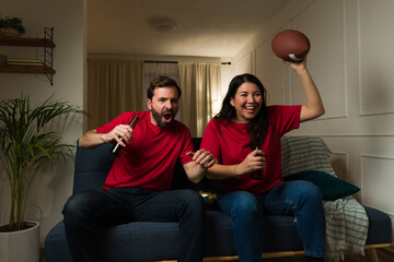 Cheerful boyfriend and girlfriend excited watching a soccer game at home © AntonioDiaz