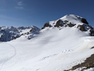 Snow topped alpine mountain rock blue sky snow tracks