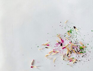photo of pink and green wooden shavings from pencils, a powdered pencil core that remains after sharpening on white paper, top view, close up 