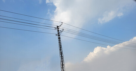 Electricity pylon with blue sky and white clouds background. Power transmission.
