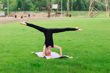 Preteen child gymnast performs an exercise on sport mat. Teenager fitness in nature. Yoga and...