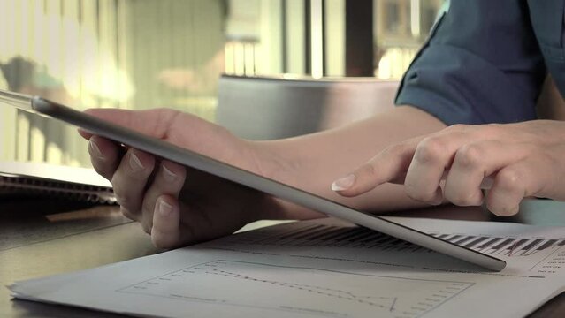 Business woman at the cafe is working on financial graphics with a tablet