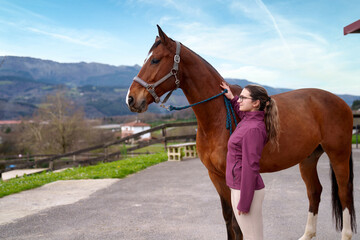 Obraz premium A serene outdoor setting frames a young equestrian as she lovingly bonds with a majestic bay horse.