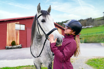 Young equestrian woman pets her horse, enjoying the outdoors.