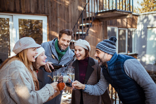 Group of happy friends enjoying champagne in winter outdoors