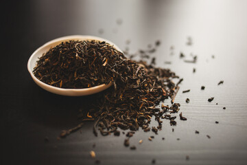 Liquid tea in a bowl sits beside a stack of tea leaves on a table