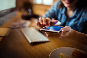 Young woman using smartphone during coffee break at home office
