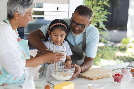 Biracial grandparents and granddaughter enjoy baking together at home