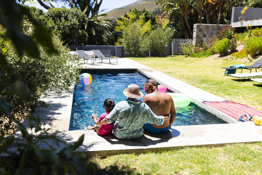 Biracial grandparents and granddaughter enjoy poolside fun at home with copy space - Powered by Adobe