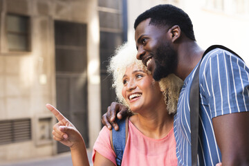 A diverse biracial couple shares a joyful moment outdoors in the city with copy space