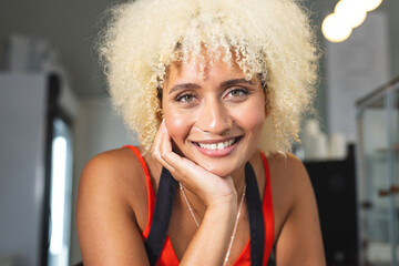 A young biracial female cafe owner barista smiles warmly at the camera