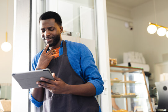 African American man reviews inventory on a tablet at a bakery, with copy space