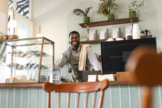 African American businessman smiles behind the cafe counter