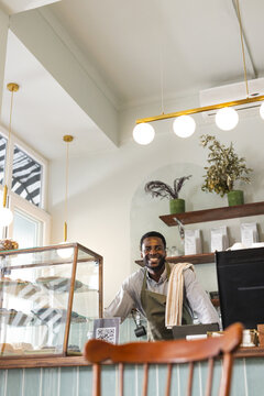An African American male barista stands behind a cafe counter, with copy space