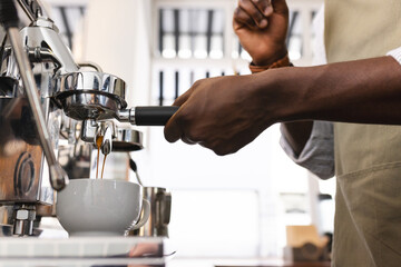 An African American barista prepares espresso at a coffee machine