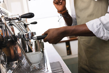 An African American barista prepares coffee at an espresso machine