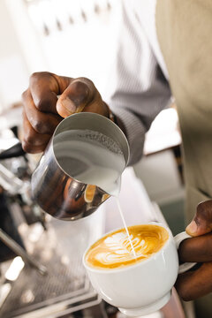An African American barista crafts a latte at a coffee shop