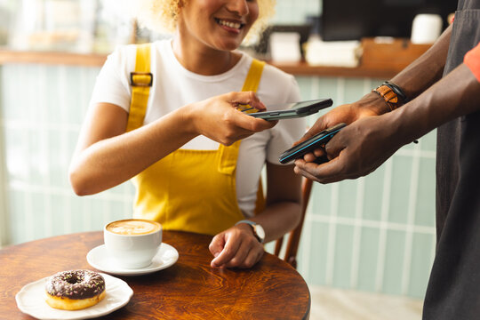 Young African American man pays with phone at a cafe