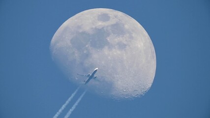 Photograph of the moon while a plane passes in front. Travel by plane next to the moon. Space travel