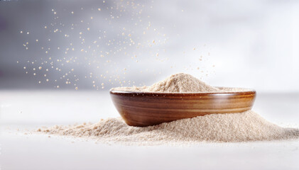 A wooden bowl filled with a heaping pile of nutritious wheat flour with some flour scattered on the table and gray background